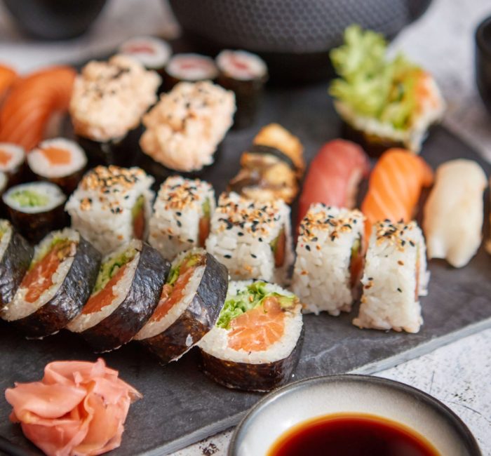 assortment-different-kinds-sushi-rolls-placed-black-stone-board-traditional-asian-iron-tea-pot-side-top-angle-view (1)